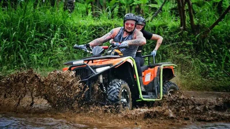 Quad bikers navigating through muddy trail during rainy season near Hanoi