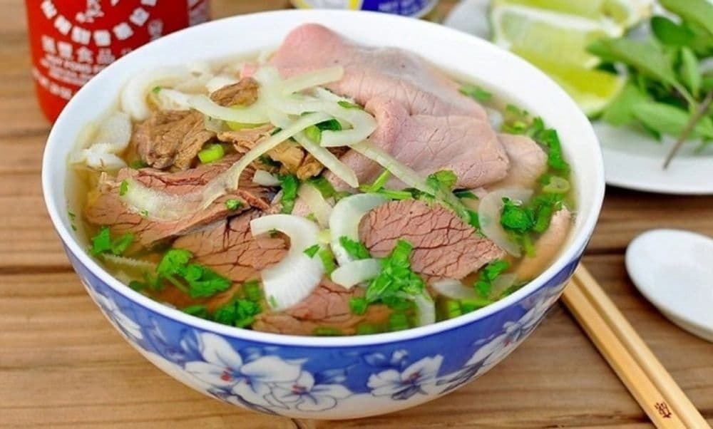 Steaming bowl of authentic Hanoi pho with herbs and lime