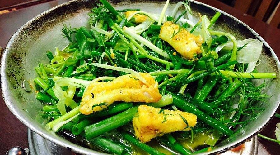 Traditional Cha Ca fish dish being prepared at a table in Hanoi