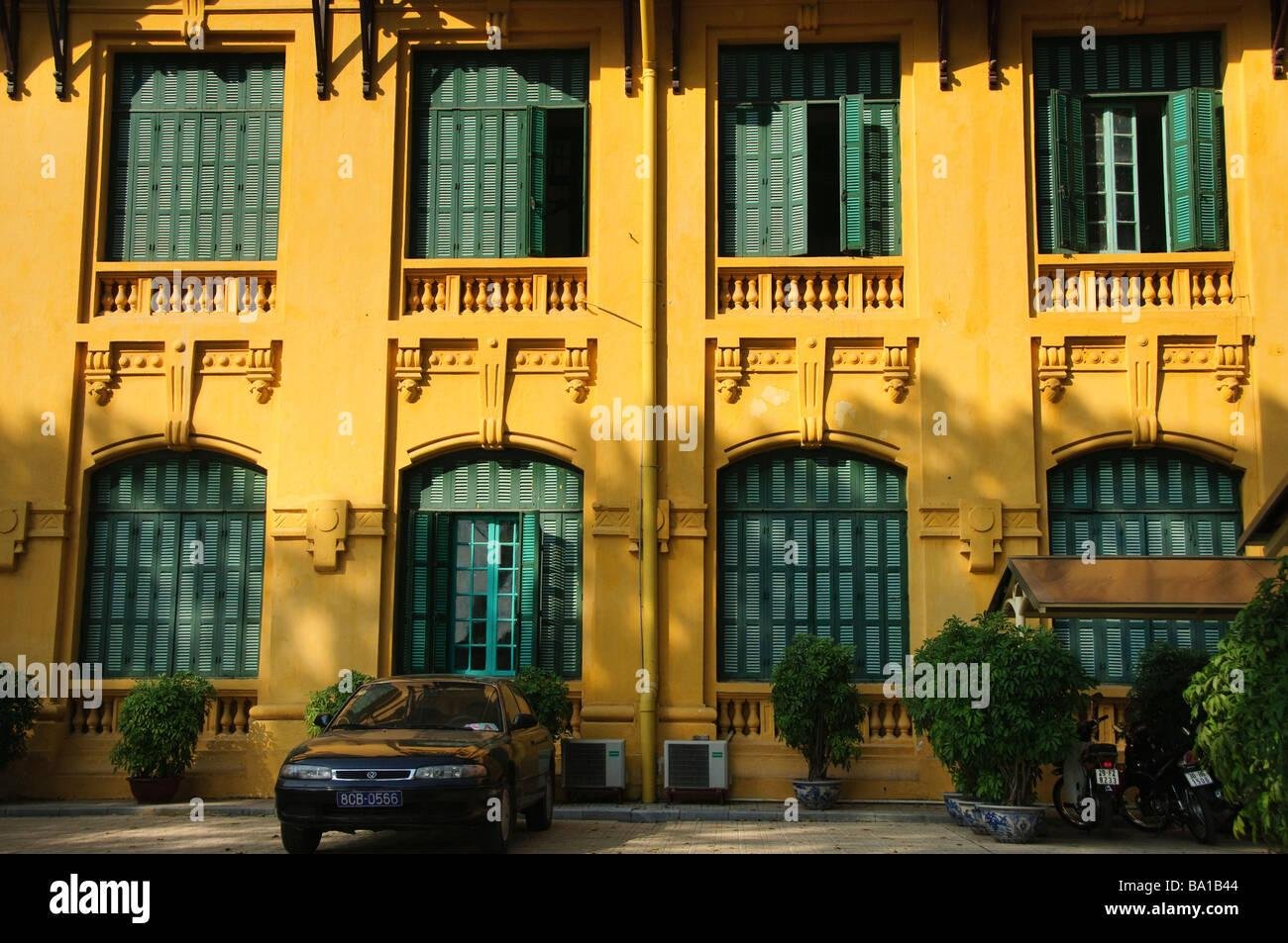 Row of yellow French colonial buildings with shuttered windows and balconies in Hanoi Old Quarter