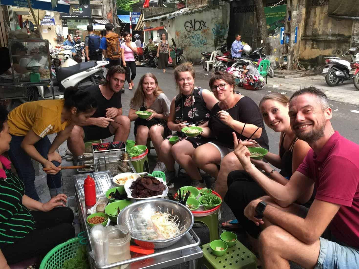 Guide explaining Vietnamese street food to tourists during a walking tour in Hanoi