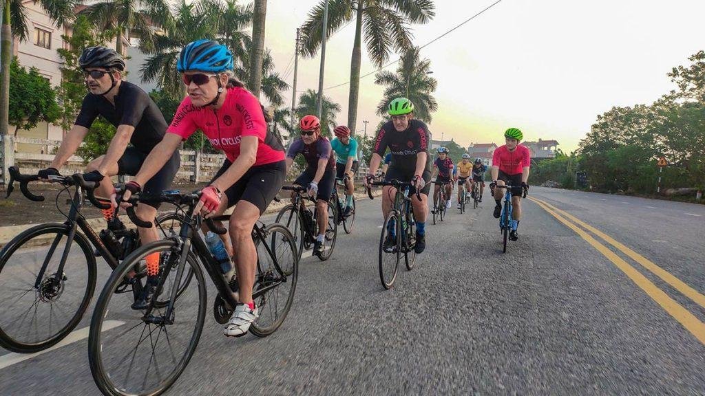 Group of cyclists safely navigating a Hanoi intersection with hand signals