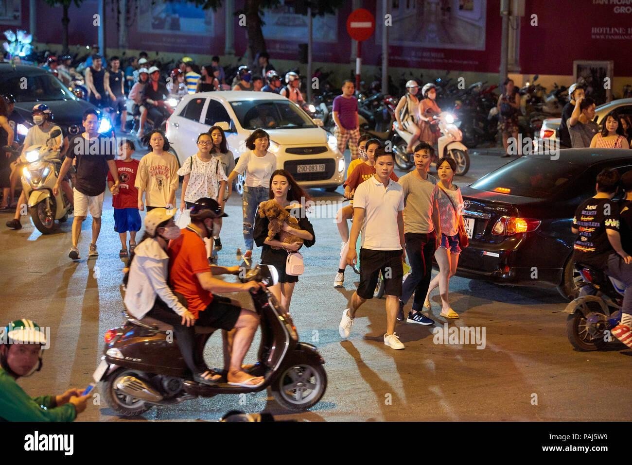 Pedestrians crossing a busy street with motorbike traffic in Hanoi