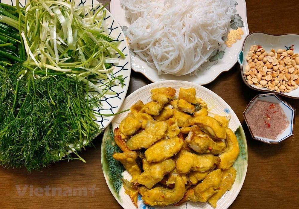 Traditional Cha Ca La Vong being prepared tableside with fresh herbs and spices