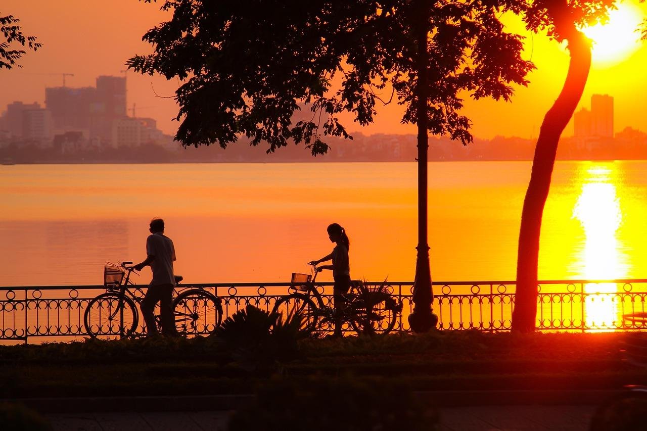 Panoramic view of cyclists riding along West Lake in Hanoi