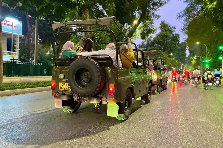 Jeep food tour exploring bustling Hanoi night market with colorful lights