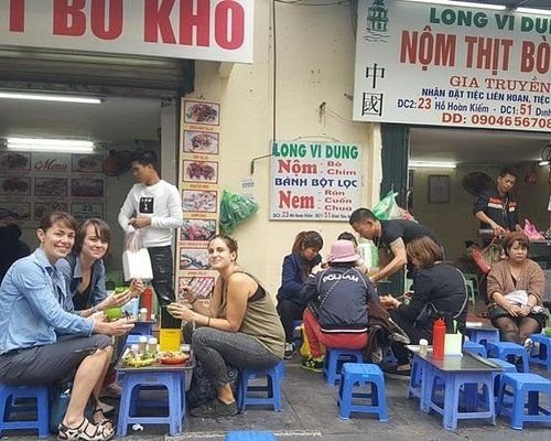 Travelers interacting with local food vendors in Hanoi