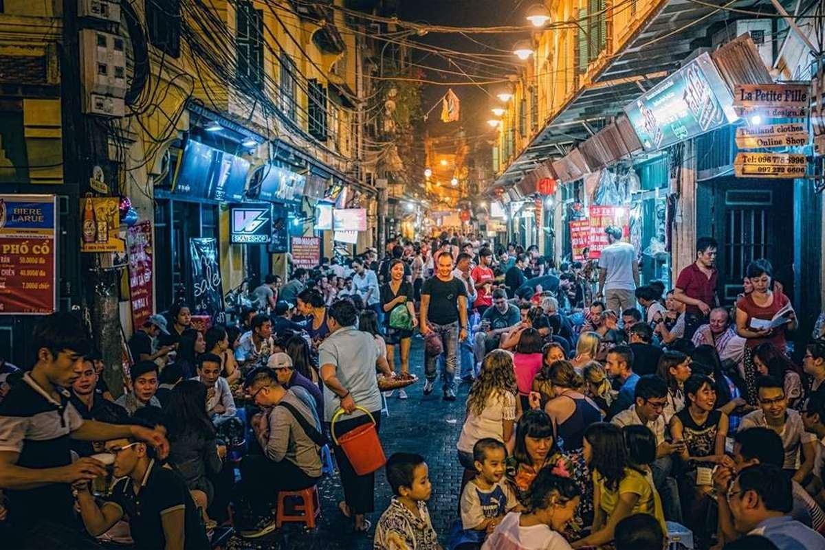Atmospheric night scene in Hanoi Old Quarter with street vendors and diners on small stools