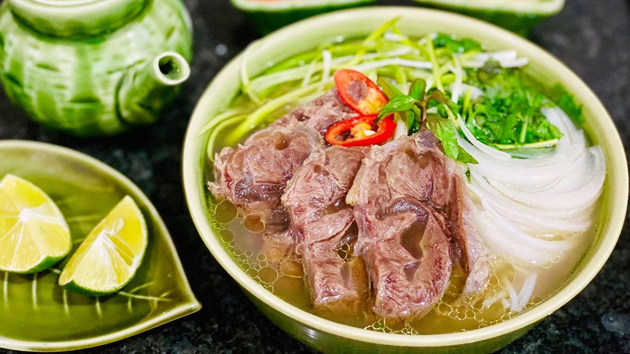 Steaming bowl of traditional Hanoi Pho with fresh herbs and lime