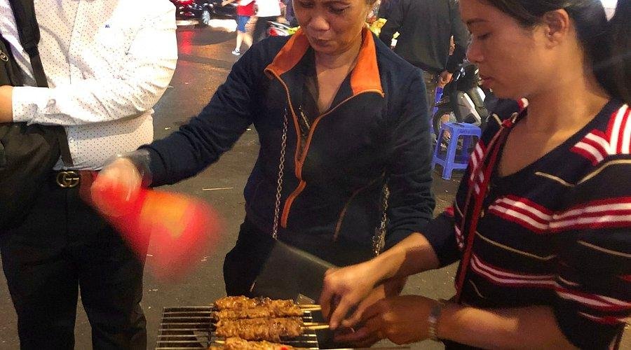 Tourist ordering from a Hanoi street food vendor at night