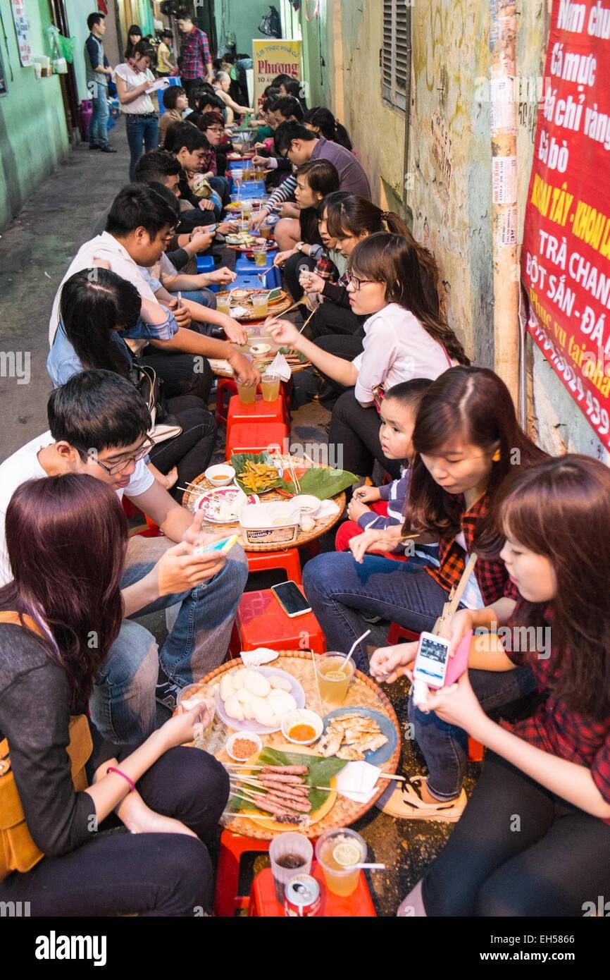Locals eating on plastic stools at street food stall