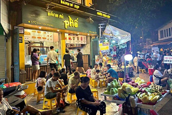 Properly dressed tourists enjoying street food in Hanoi Old Quarter