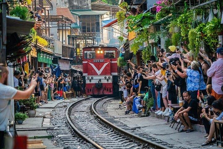 Street food vendors preparing dishes near train tracks