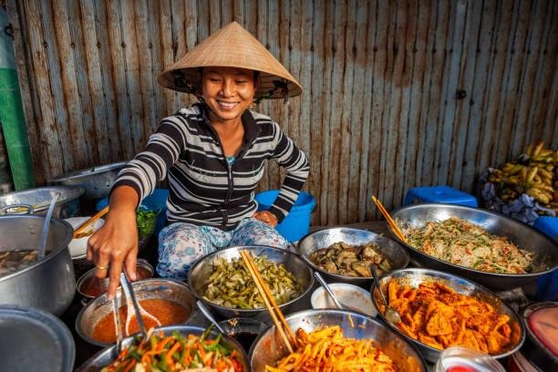 Local Vietnamese street food vendor cooking traditional dishes in Hanoi at night