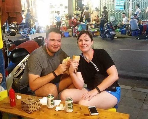 Tourists interacting with friendly Hanoi street food vendor