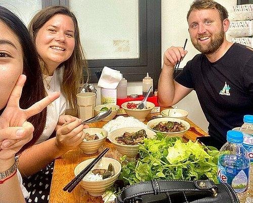 Local guide explaining Vietnamese street food preparation to small tourist group