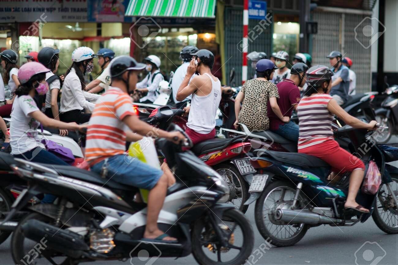 Busy motorbike traffic in Hanoi streets with riders wearing helmets