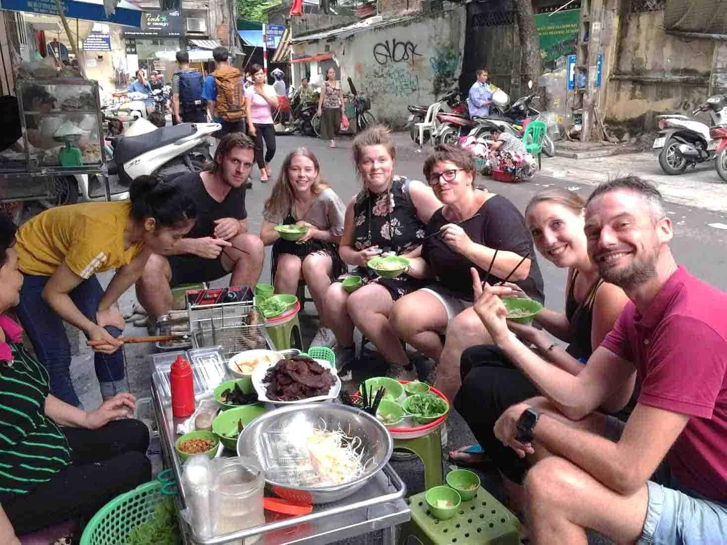 Tourists enjoying street food during a walking tour in Hanoi