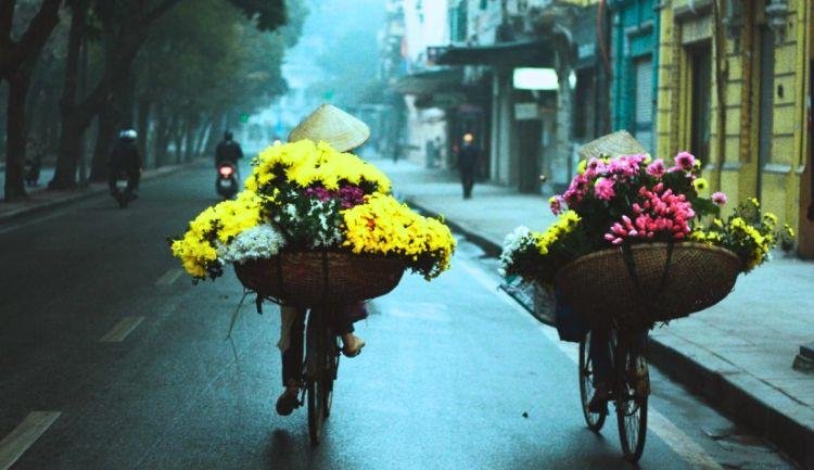 Cyclists in light jackets exploring misty morning streets of Hanoi in winter