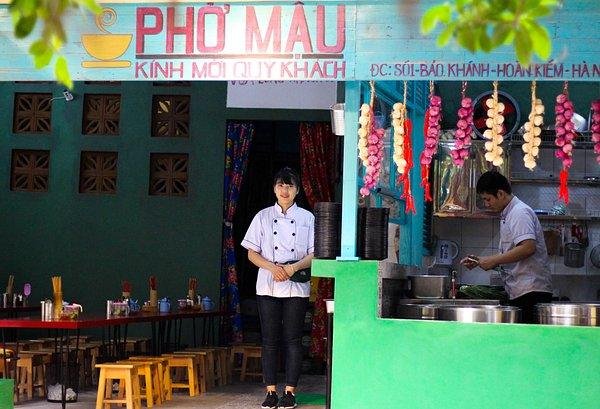 Local Vietnamese eating breakfast at street food stall with small stools