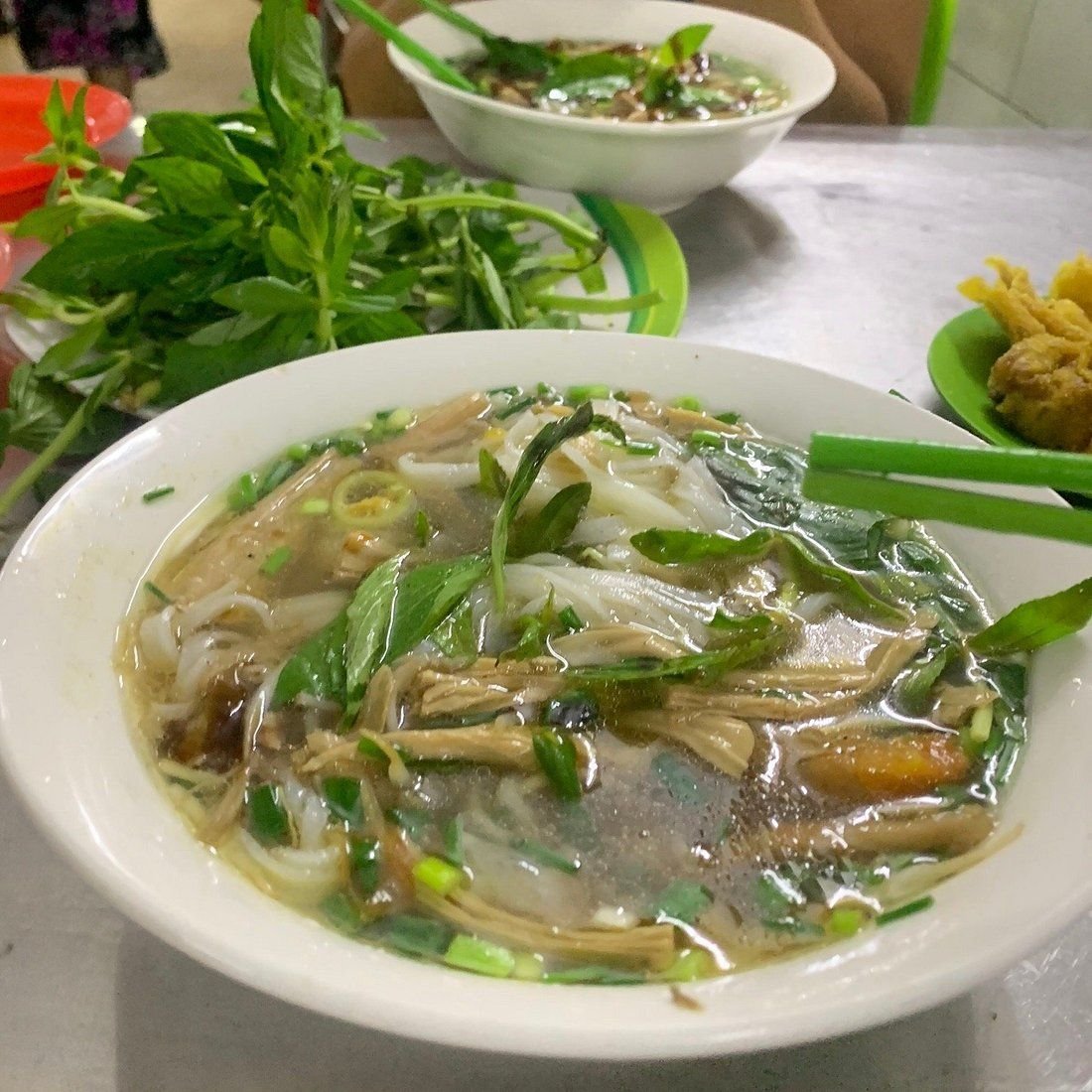 Steaming bowl of pho chay with fresh herbs and mock meat