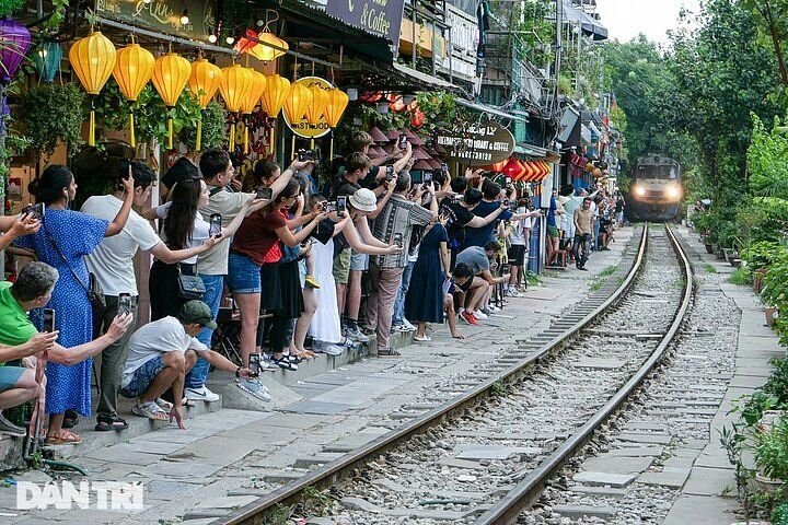 Train approaching on Hanoi Train Street with tourists watching