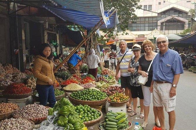 Vegan travelers exploring a traditional Hanoi market after their Vespa food tour