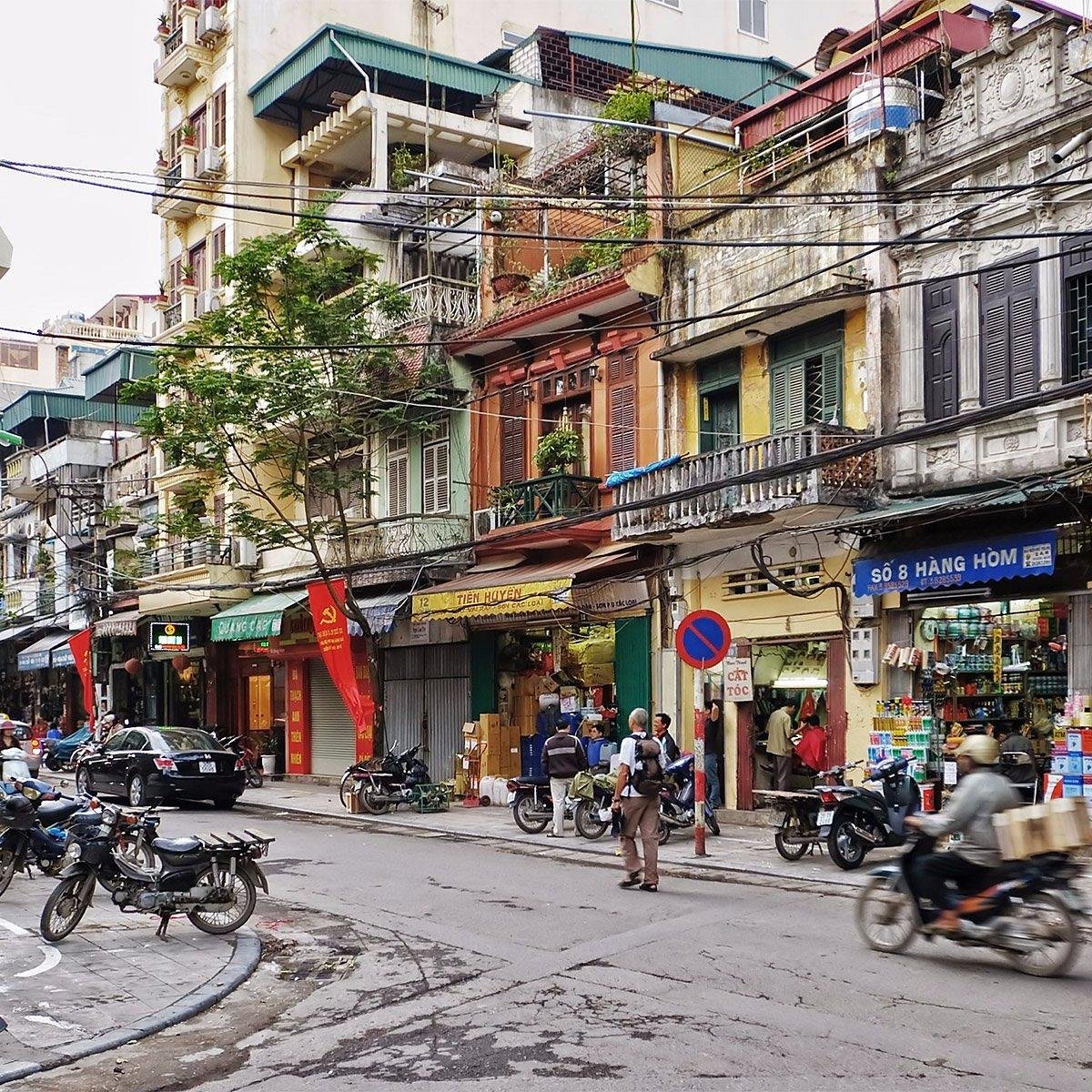 Vietnam Travelers guide leading tourists through the historic streets of Hanoi Old Quarter