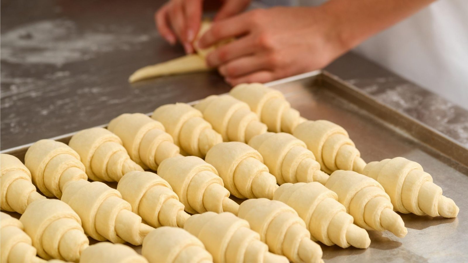 Vietnamese baker carefully shaping croissant dough using traditional French techniques