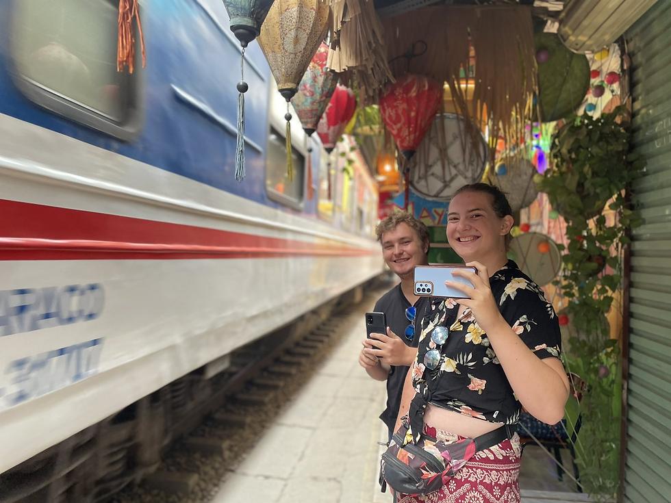 Local people enjoying coffee on small stools near train tracks