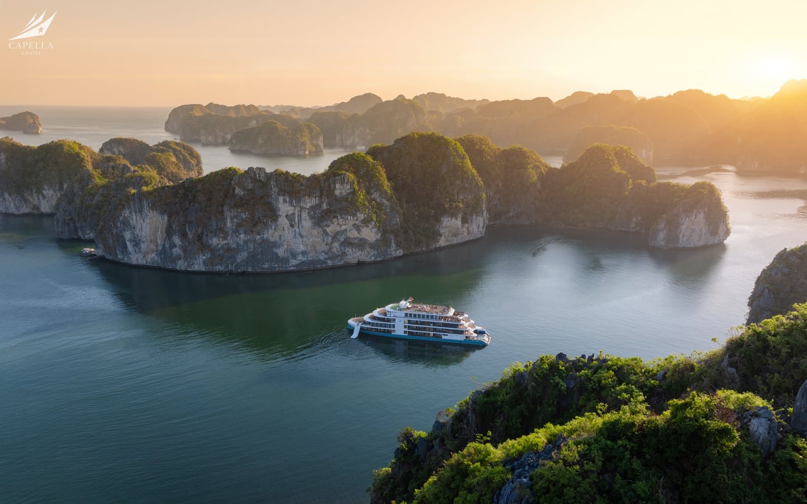 Elegant cruise ship moving through clear blue Ha Long Bay water