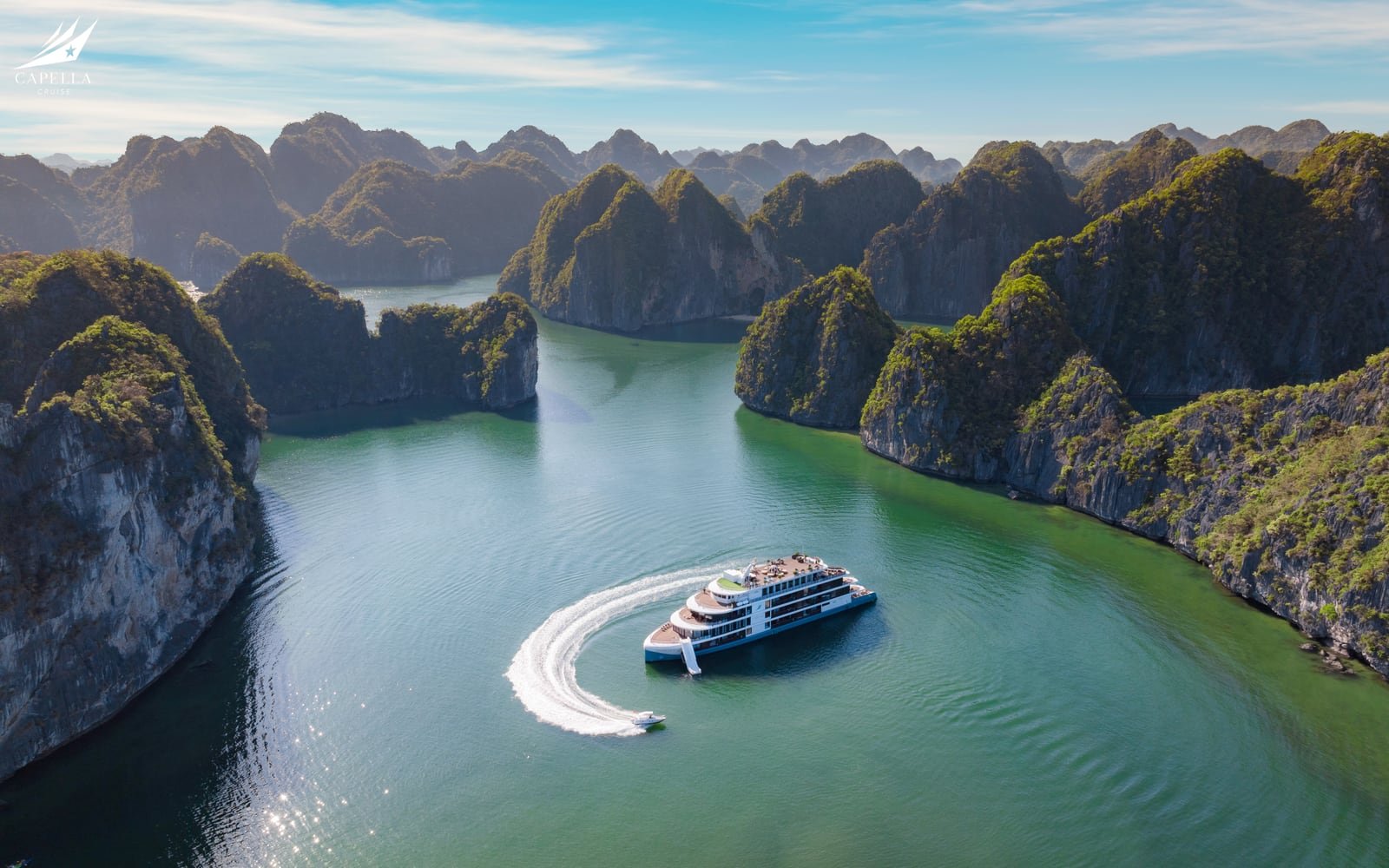 Elegant cruise ship moving through clear blue Ha Long Bay water