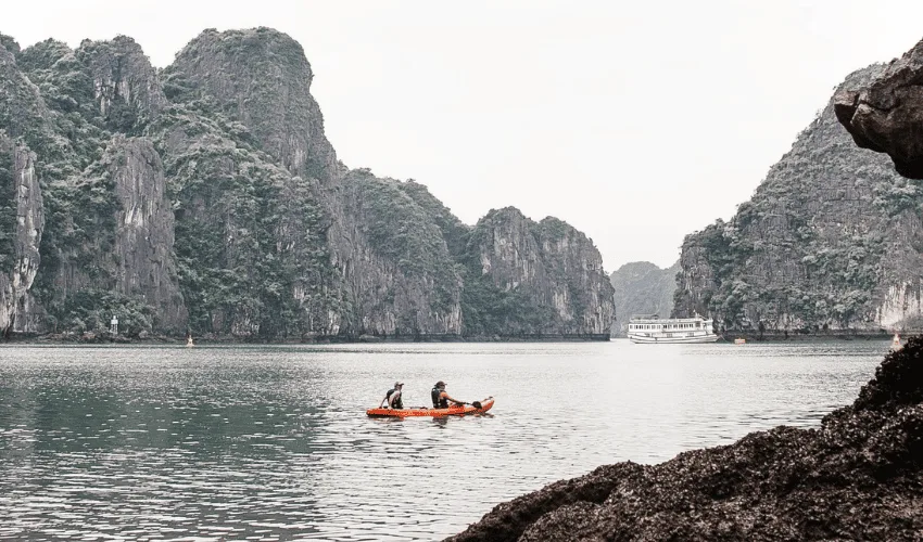 Travelers kayaking among limestone islands in Ha Long Bay Vietnam