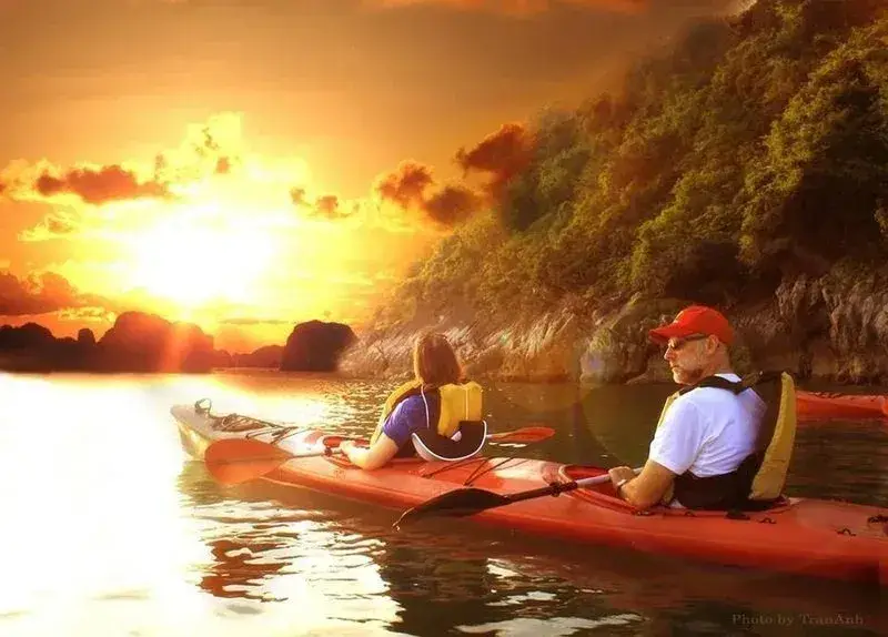 Travelers kayaking between limestone cliffs during sunset